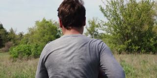 一个穿着轻便运动服的白人青年在一个绿色的公园里跑步