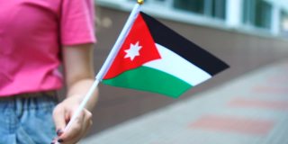 拿着约旦国旗的陌生女子。女孩举着约旦国旗走在大街上