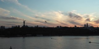 顶部鸟瞰图彩色的夏夜天空。与垂钓者在第聂波罗河上驾驶摩托艇，日出日落。乌克兰城市基辅湖上的桥梁景观。水路运输、旅游