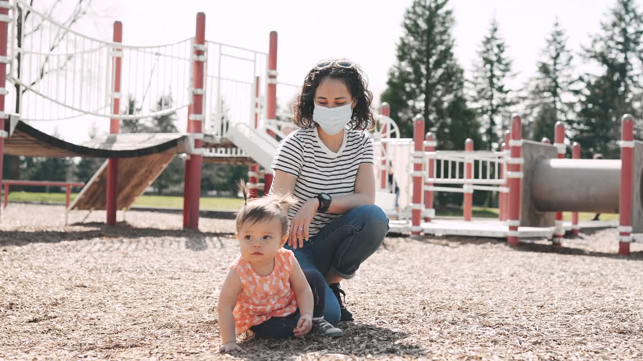 种族母亲和蹒跚学步的女儿在公园玩耍