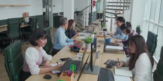 亚洲白领们在自己的办公工作站里忙碌地工作和交流，在开放式的规划中，心情愉快