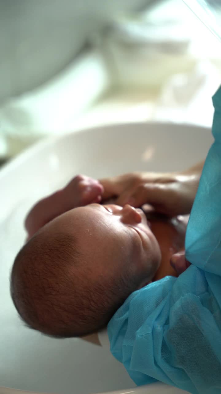 婴儿护理员在浴室为新生儿洗澡