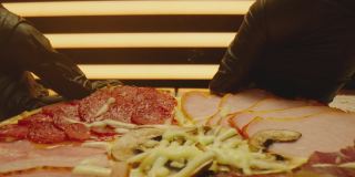 手拿起一块披萨。美味的披萨被切成块的特写镜头。美味的烤披萨配火腿、融化的芝士、红辣椒。ARRI ALEXA用老瓦镜头拍摄。相机移动