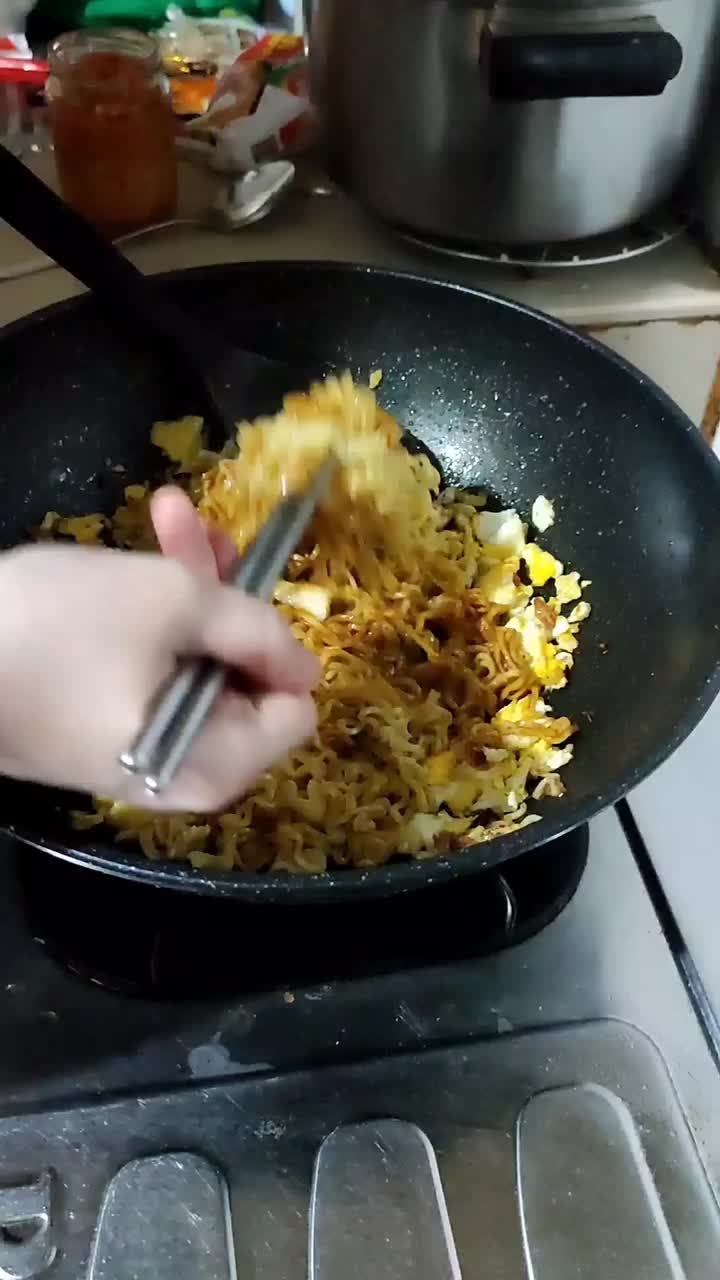 在家里的厨房里做方便面的过程。炒鸡蛋面条。