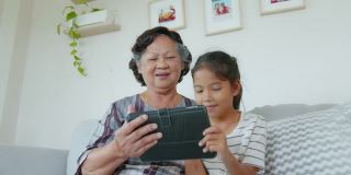 孙女正在客厅里帮奶奶用ipad。