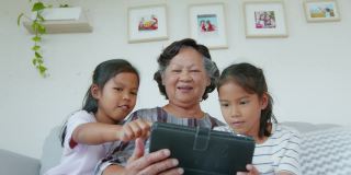 在客厅里，两个孙女一起帮奶奶用ipad。