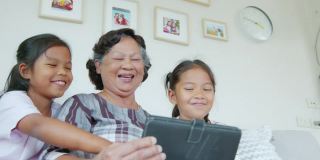 两个孙女一起在客厅里帮奶奶用ipad。