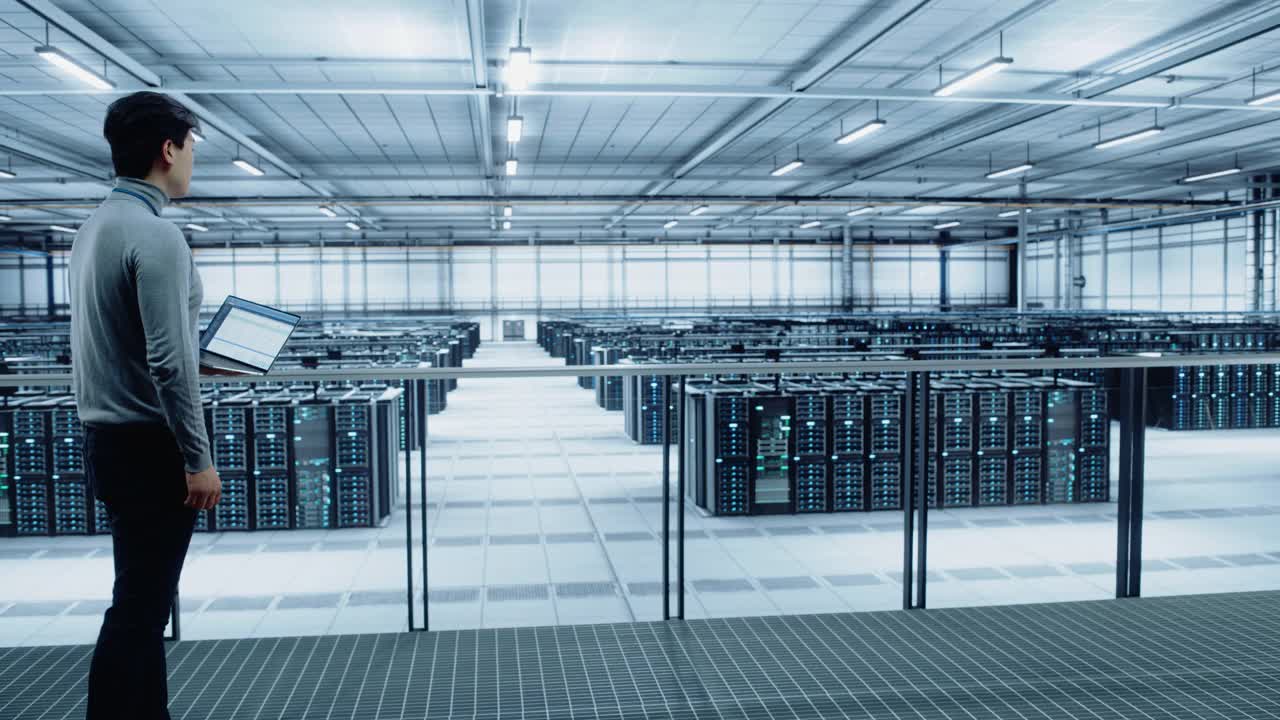 数据中心工程师使用笔记本电脑。服务器群云计算专家设施与亚洲男性系统管理员与数据保护网络为网络安全工作。