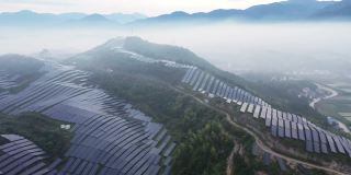 无人机在晨雾中观察山顶上的太阳能发电厂
