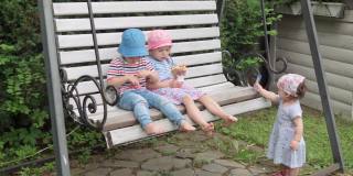 快乐的孩子们在花园秋千椅上吹肥皂泡。阳光明媚的夏日，男孩和女孩女儿和儿子在田园般的郊区房子后院草坪上玩得很开心。童年时期,家庭的概念