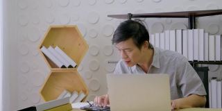 在家庭办公室工作的亚洲老人因业务压力过大。从笔记本电脑检查后
