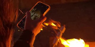 一个女人在火坑里烤棉花糖并拍摄它-移动拍摄