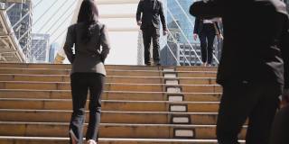 慢动作镜头。一群西装革履的亚洲商务人士正忙着走在去往办公室的楼梯上。