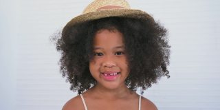 美丽可爱的非洲小女孩的肖像站着微笑，卷发发型和镜头在摄影棚。