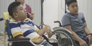 教室里坐轮椅的亚洲残疾儿童。自闭症儿童在学校学习中的活动。培养孩子的大脑和想象力。