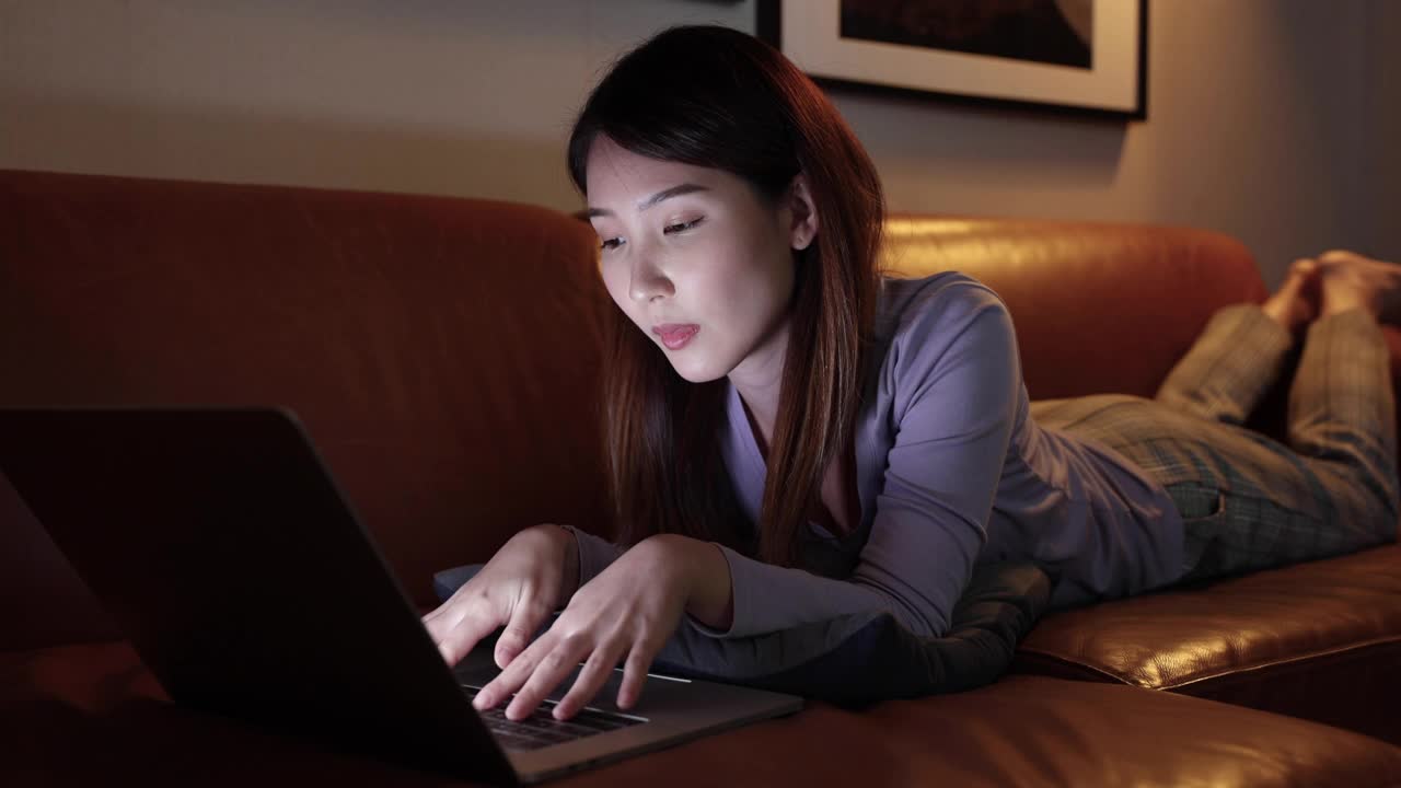 亚洲女性晚上使用笔记本电脑，她有眼睛刺激，蓝光对眼睛有害。