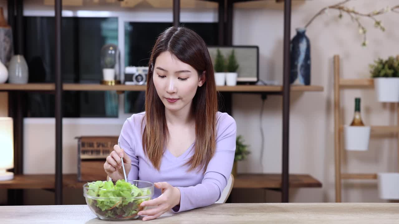 一位亚洲妇女拒绝吃她最喜欢的面包，而选择健康的沙拉