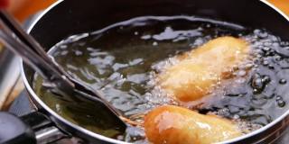 香肠串裹上面糊，放在厨房炉子上的平底锅里用热油煎。自制玉米热狗。烹饪过程。