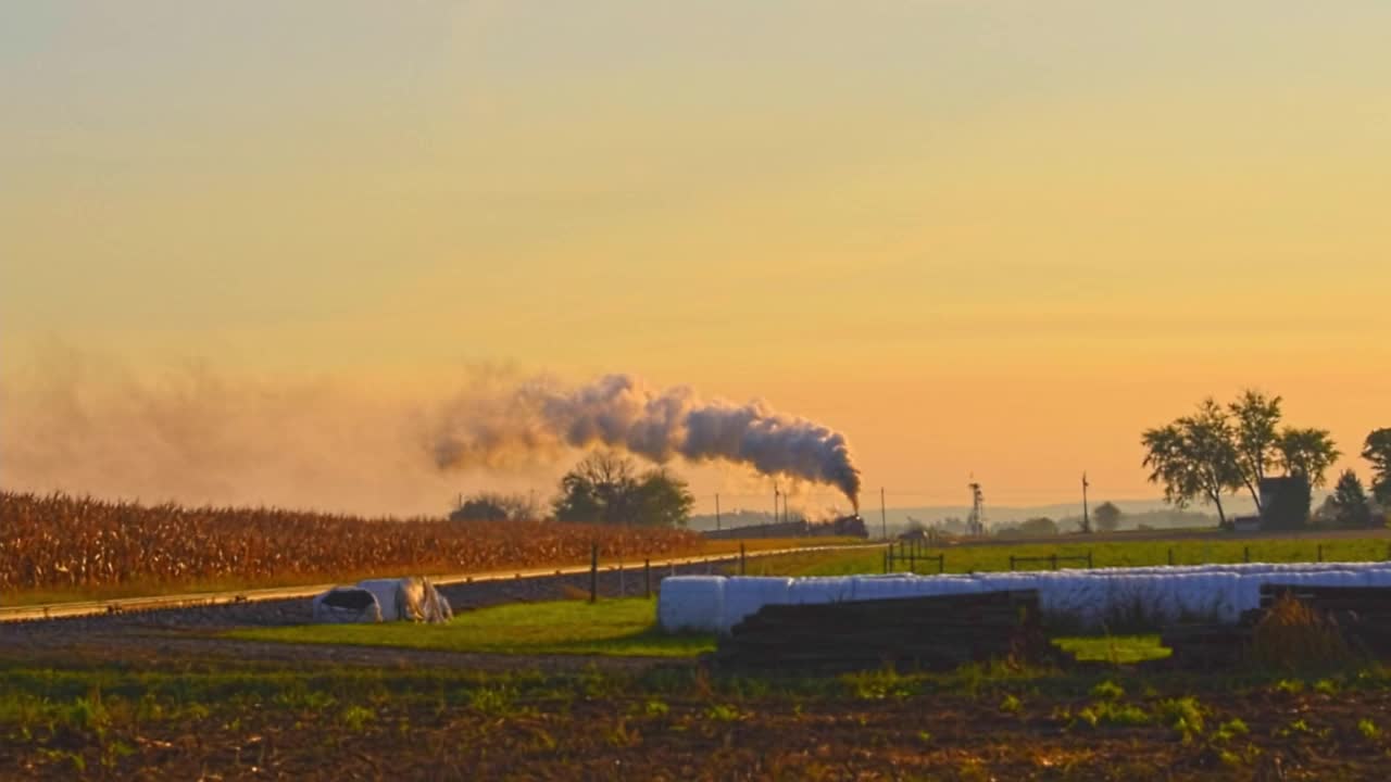 黄金时刻的日出，满载蒸汽的旅客列车驶近。