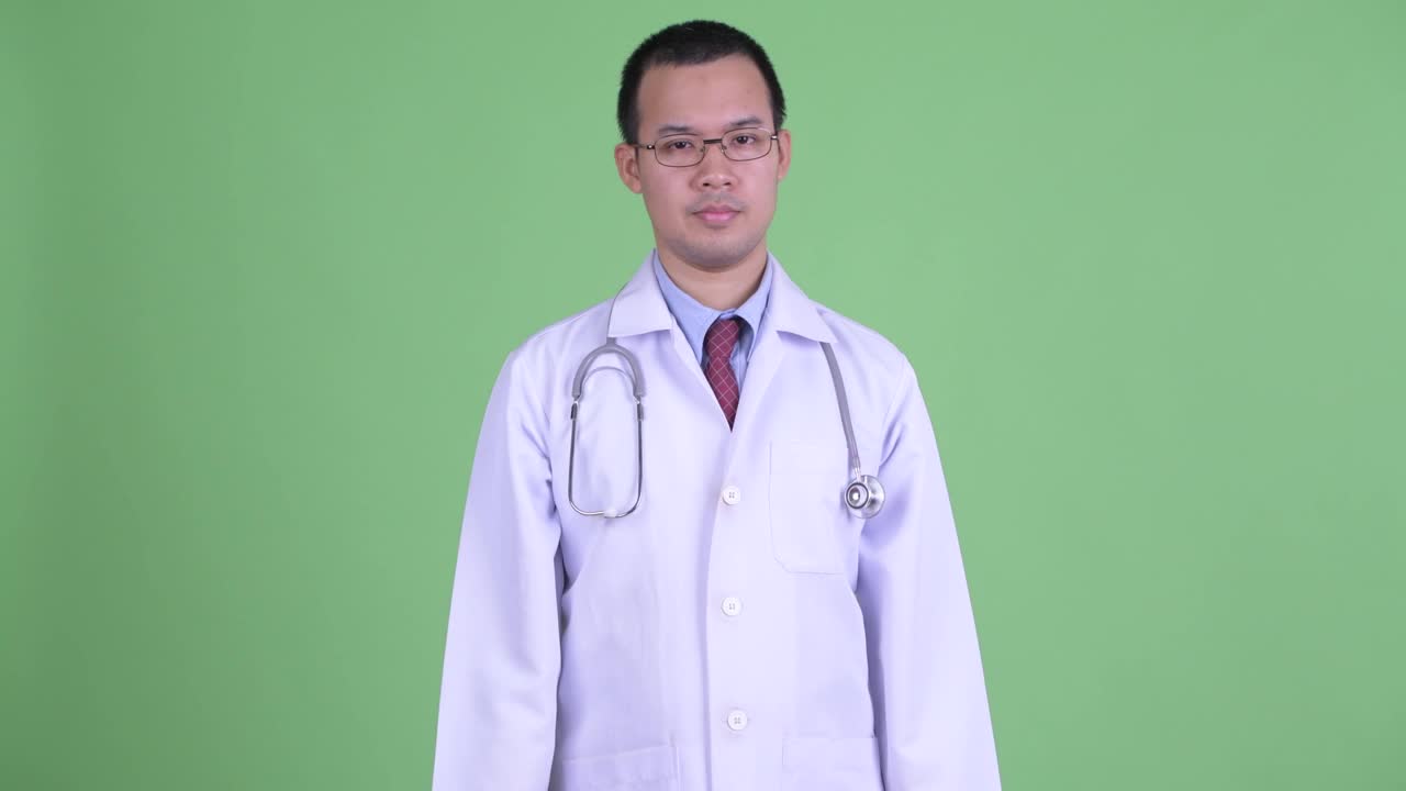 亚洲男医生的画室肖像在绿色背景下耸肩