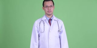 亚洲男医生的画室肖像在绿色背景下耸肩