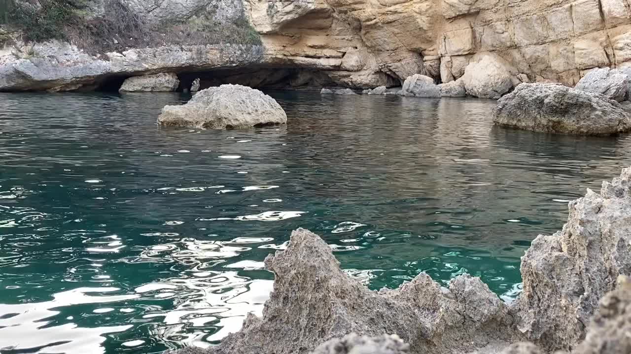 天堂海泻湖与神秘的洞穴洞穴的海岸岩石。美丽的地中海风景。夏夜碧绿闪亮的海景。壮观的石灰岩悬崖。