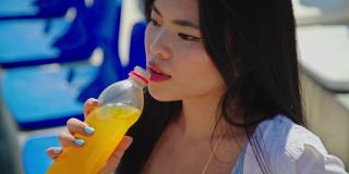 在大热天喝桔子汽水的年轻亚洲女人