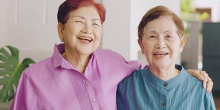 两位亚洲(泰国和中国)大姐面带爱心，对着镜头微笑，展现了她对幸福、自信、健康的退休家庭的积极享受。