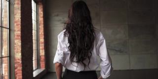 一个陌生的黑发女商人穿着白衬衫走过办公室