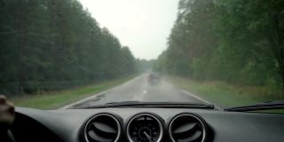 雨天在路上的汽车仪表盘和装有雨刷的前窗。