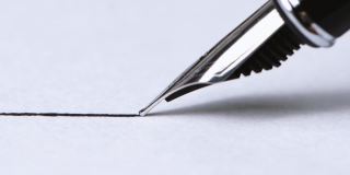 特写镜头:一支钢笔在有纹理的纸上画出一条笔直的墨线