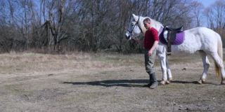 一个农民牵着一匹白马的缰绳，背景是春天的大自然。