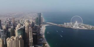 从四轴飞行器垂直平移。迪拜，海滩和摩天大楼的航拍。