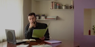 一个男人在他的办公室工作的高清视频，商人的概念，在家工作，打电话，用他的笔记本电脑，严肃，紧张，担心，扔他的文件和文件。