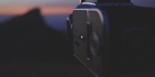 三脚架剪影胶卷相机拍摄日出的山