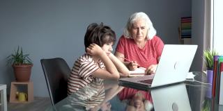 老奶奶和孙子在家里使用笔记本电脑