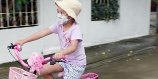 亚洲女学生戴着医用口罩，骑着自行车或自行车度假。