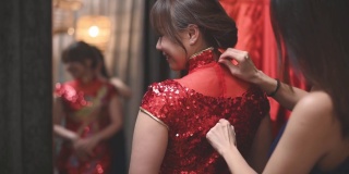 在传统精品店，一名亚洲华人女子在姐姐的帮助下，对着镜子试穿中国传统旗袍