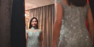 亚洲华人女子在传统精品店试穿中国传统旗袍，对着镜子微笑