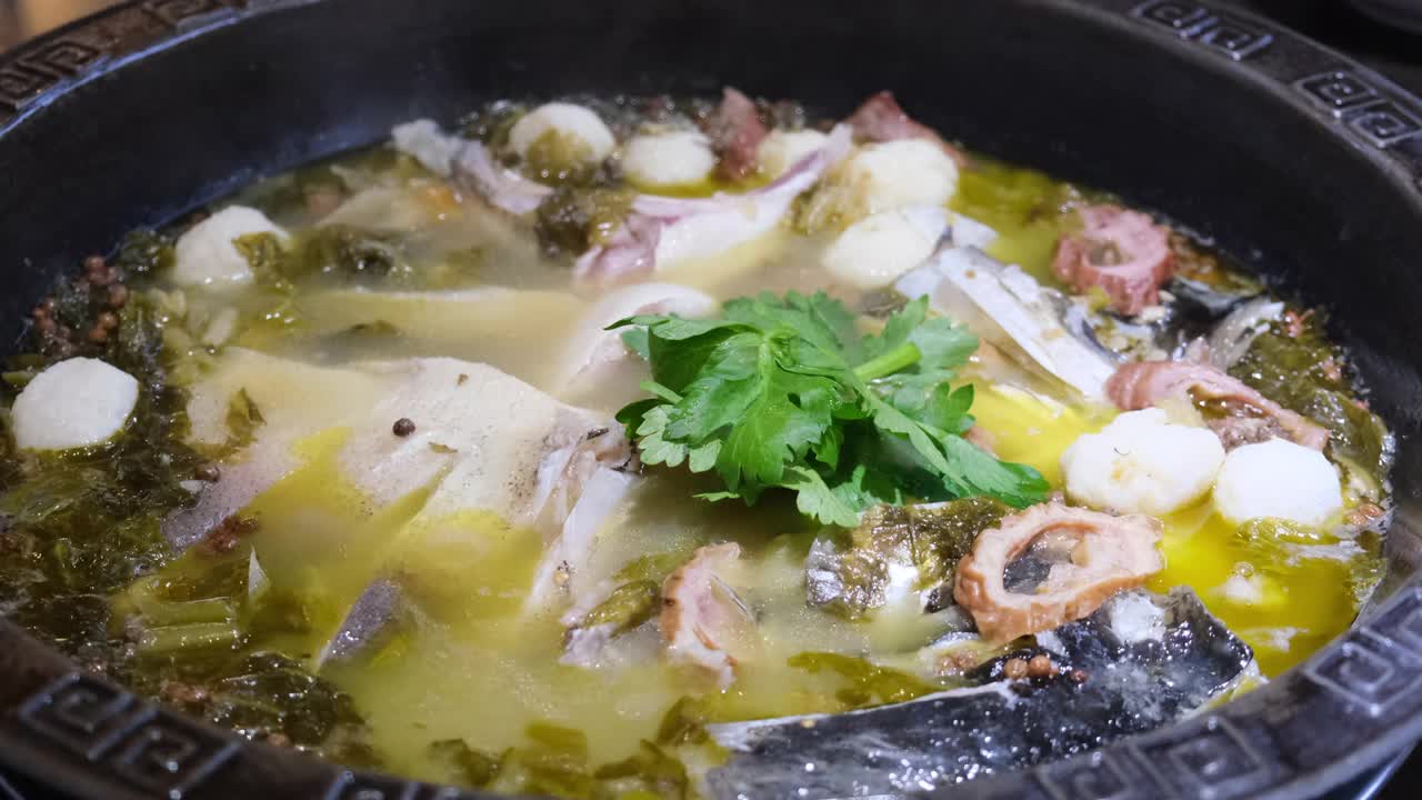 将滚烫的辣椒油倒入鱼汤和酸菜中。缓慢的运动。