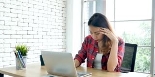 经济衰退压力女性使用笔记本电脑在家办公头痛，疲惫的失败业务挫折。压力大的亚洲女性焦虑过度工作，痛苦与生活危机累压力大的失业