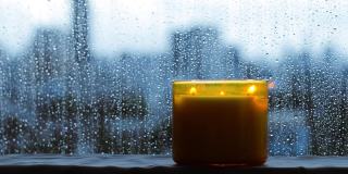 燃着香气的蜡烛放在有雨滴的窗旁
