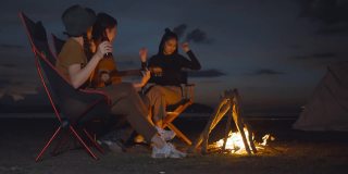50p帧率的镜头，年轻人弹吉他，在跳舞的气氛中快乐地唱歌，围绕着篝火露营，旅行的概念，冒险，热爱自由。