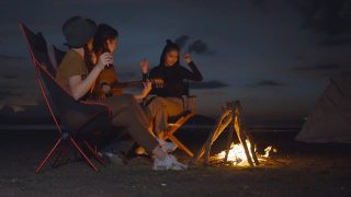 50p帧率的镜头，年轻人弹吉他，在跳舞的气氛中快乐地唱歌，围绕着篝火露营，旅行的概念，冒险，热爱自由。视频素材模板下载