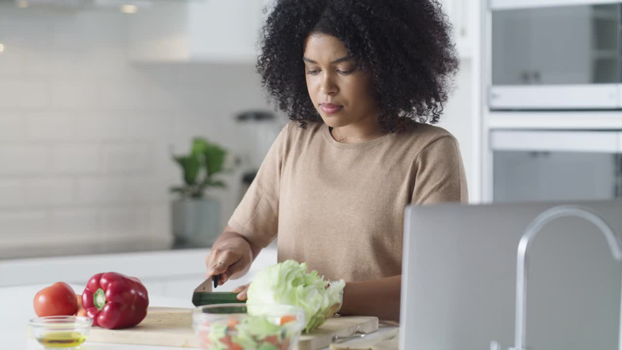 一段4k视频记录了一名年轻女子在家里用笔记本电脑准备一顿健康大餐
