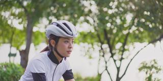 亚洲年轻美女晚上在公园里骑车健身。运动员健美和坚定的女孩在运动服锻炼自行车运动为她的健康健康。
