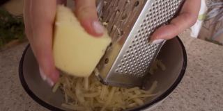 自制的奶酪卷。白干酪面包。用刨丝器把奶酪磨碎
