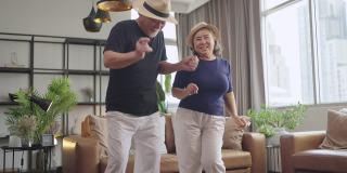 亚洲老年幸福夫妇居家隔离的概念，亚洲老年退休夫妇在客厅一起跳舞，快乐快乐的时刻，可爱的老年夫妇在家里跳舞