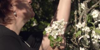 一名白人女士正在享受苹果树花香的特写镜头。