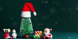 圣诞快乐，新年快乐的雪花飘落与圣诞树和圣诞老人，雪人和礼物盒在深绿色的背景